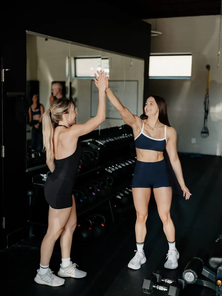 Two SWC members mid-workout, reaching up for a high-five